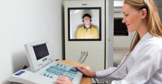 Fonoaudióloga realizando audiometria com paciente em cabine acústica